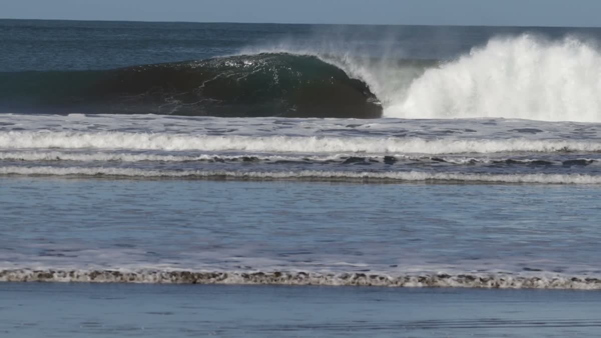 A wide shot of an empty wave peeling along the reef.