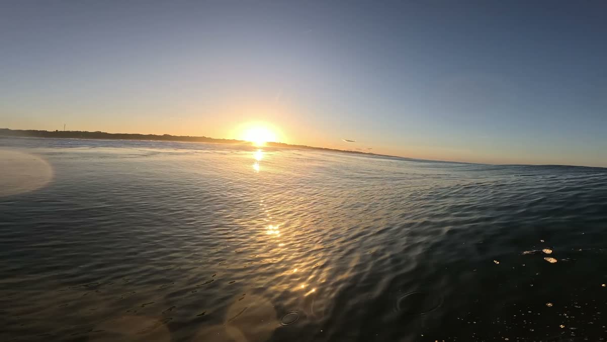 Sunset over glassy water, from the lineup.