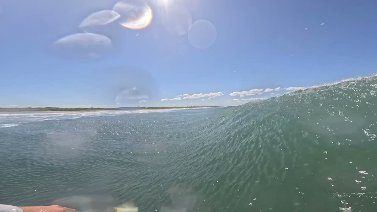 Point-of-view shot of a wave face under a bright sky.